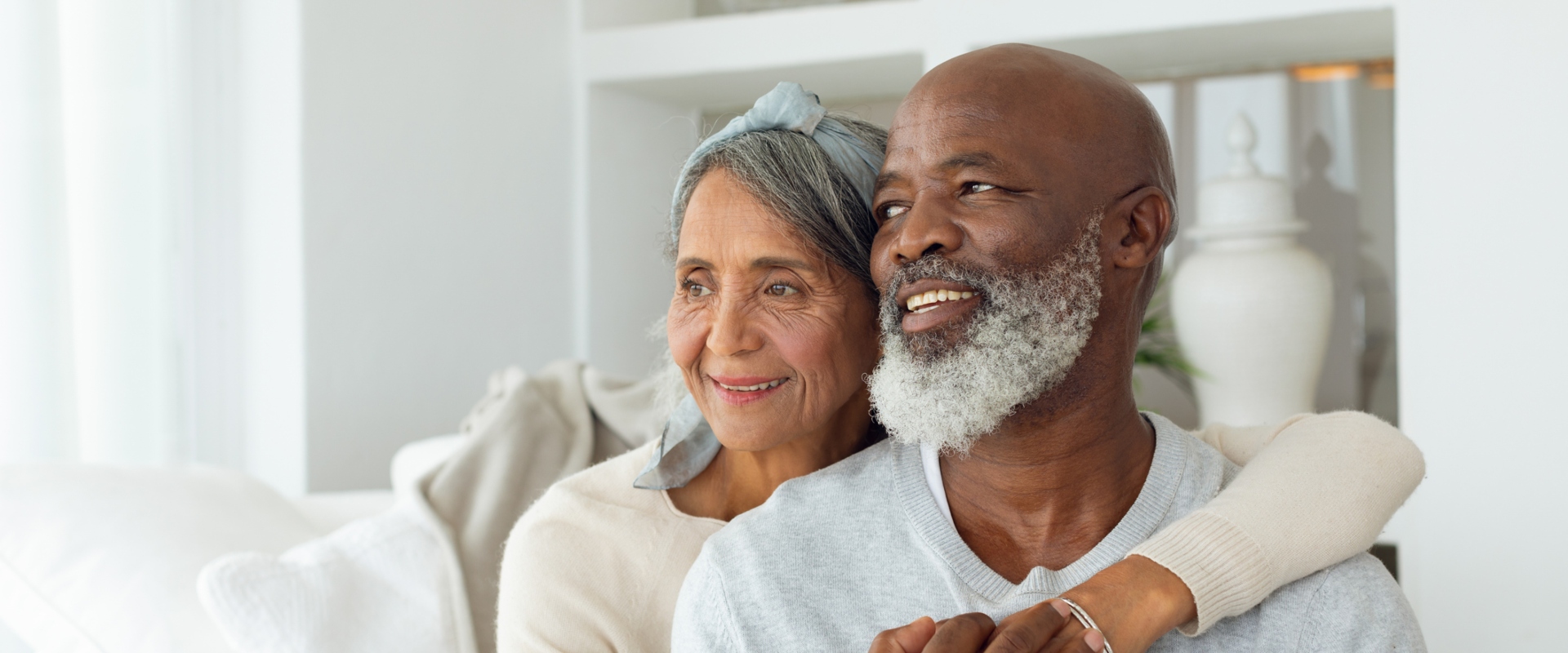 Front view of senior diverse couple sitting on a white couch in beach house